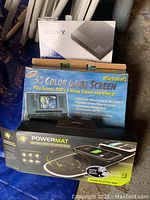 Sony Blu-ray/DVD player box behind Intec 5" Color Game Screen box and Powermat wireless charging mat box.
