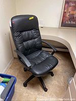 Full view of black office chair with padded seat and backrest, black plastic armrests, and wheeled base.
