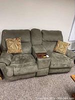 Full view of green microfiber recliner love seat with two recliner seats, center console, and two decorative pillows.