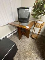 Side view of wood frame side table with four stone tile insets on top and angled wood legs. Shows surface scratches and wear.