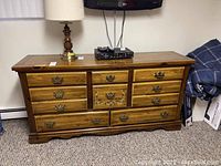 Front view of vintage wooden dresser with 10 drawers, showing overall wear and finish loss