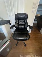 Front view of black leather office chair showing padded seat, backrest, armrests, and casters.