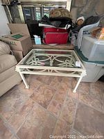 Front angle showing the decorative metal frame and glass top of the coffee table with surrounding boxes and couch.