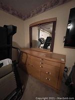 Front angled view of wooden dresser with attached mirror, showing drawers, cabinet doors, and handle hardware.