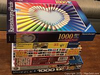 Stacked jigsaw puzzle boxes showing puzzle titles and piece counts