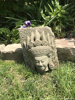 Front view of hand carved stone garden decoration showing detailed face and headdress.