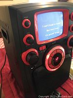 Front angle showing karaoke machine screen with lyrics displayed, power and volume knobs visible