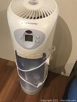 Full view of front of humidifier showing digital control panel, water canister and power cord wrapped around unit.