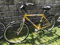 Full view of the yellow Specialized Rockhopper bike showing frame, tires, pedals, seat, and handlebar with front and rear fenders in grassy outdoor setting.