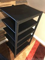 Front angled view of the black 5-tier audio stand showing five shelves with paint chips and scratches.