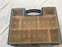 Closed view of Mastercraft storage box showing transparent lid with internal compartments visible, and orange handle.