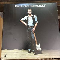 Front cover of Eric Clapton Just One Night double LP album. Image shows Eric Clapton standing with guitar against black background and the album title.