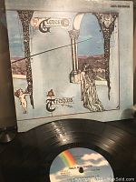 Front cover of the Genesis LP album Trespass showing artistic classical design with figures and arches, MCA Records label, vinyl record partially visible