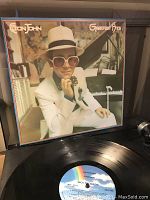 Front cover of Elton John Greatest Hits vinyl album showing Elton John seated at piano.