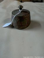 Side view of the Moroccan style snuff box showing detailed engraved and colored metal pattern and attached tag.