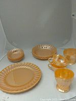 Photo showing the set of Fire King Peach Lustre dishes including plates, bowls, cups, and creamers on a white backdrop.