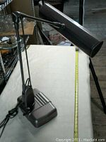 Side angled view of the metal office lamp showing the adjustable arm and rectangular light head in iridescent light brown on a white background.