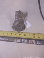 Front and side views of the metal coat clip featuring a relief bust of Napoleon with measuring tape showing size approximately 3 inches tall.