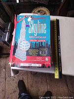 Top and front view of the original box showing American Skyline logo, instructions, and illustration of buildings constructed with the set parts. Color added to the parts is highlighted on box.