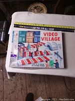 Photo of the Video Village board game box from top view showing colorful artwork and label.