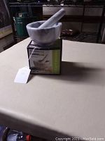 White marble mortar and pestle set displayed on the original box on table surface.