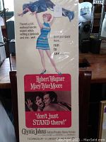 Photo of a vintage movie poster for the film 'Don't Just Stand There!' showing illustration and actor names.