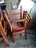 Stacked view of 4 vintage wooden ladderback chairs with red leather seats showing wear and condition.