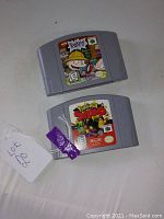 Two Nintendo 64 game cartridges on a white surface. One labeled Rugrats Scavenger Hunt and the other labeled Pokemon Snap.