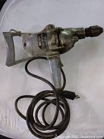 Side view of the vintage Black and Decker electric drill showing metal body and trigger handle with power cord.