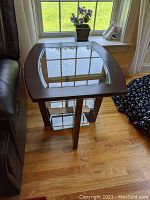 Full view of the side table showing the top glass surface and wooden frame next to a couch.