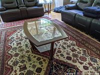 Coffee table showing glass top, dark wood frame, and lower glass shelf from one side