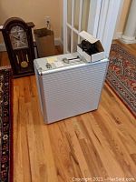 Closed aluminum carrying case with handle, small open cardboard box with charger and cables on top