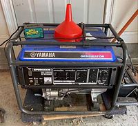 Full front view of generator showing Yamaha branding, EF6600DE label, outlets panel, Battery Tender charger and funnel on top