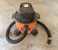 Top front angle showing the orange body and attached black hose with repair tape near hose end.