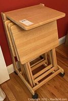 Set of three butcher block style wooden TV tray tables stacked together, showing smooth tops and folding legs with caster wheels