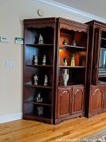 Wooden shelving unit with five figurines and vases displayed on shelves.