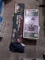 Photo showing Timber Top dome tent box alongside Coleman Powerhouse gas lantern box on the floor.