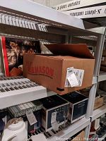 Box with assorted music CDs and vinyl LP albums visible behind, some album covers showing ABBA and other artists.