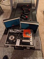 Full view of the open portable Stereo Crown record and cassette player on a treadmill, showing both detachable speakers with blue felt, control panel with buttons and knobs, turntable, and cassette deck.