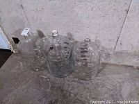 Group of three large glass winemaker's bottles placed on a basement floor against a concrete wall, showing overall size and condition.