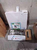 Photo shows Sony Blu-ray Disc/DVD Player in open box with cables and a TV stand box behind it.