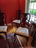 Two captain chairs at the back with arms and four side chairs in front. All with cream damask seat upholstery covered in plastic with some rips visible.