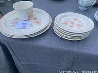 Set of stacked cream and peach floral patterned plates and sugar bowl on display surface.