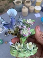 Close-up of ceramic Blue Jay figurine perched on flowers, showing detailed paintwork and design.