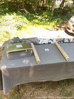 Wide shot of the lot on outdoor table, showing plastic craft box and wallpaper rolls on fabric-covered table