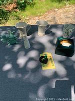 All items displayed on a dark cloth outdoors including mugs, figurine, and decorations.