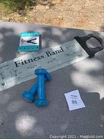 Set of Pilates book, two blue 2-pound weights, and a fitness band with printed exercise instructions