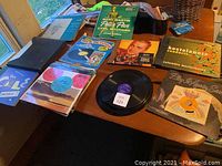 Photo showing a collection of vinyl records on a table with colorful covers featuring Mary Martin's Peter Pan, Percy Faith, Arthur Fiedler, John Denver, Play it Again Sam, and Marvel Comic Age Spectacular among others.
