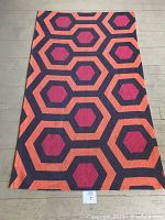 Full view of rectangular throw rug laid flat on wooden floor, showing overall pattern and size.