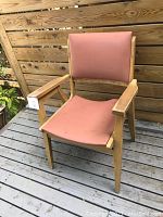 Side view of wooden Mid-Century Modern side chair showing armrest and pink upholstered seat and backrest.